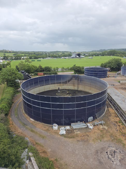 Aerial view of large circular water tanks at an industrial site amidst rural fields.